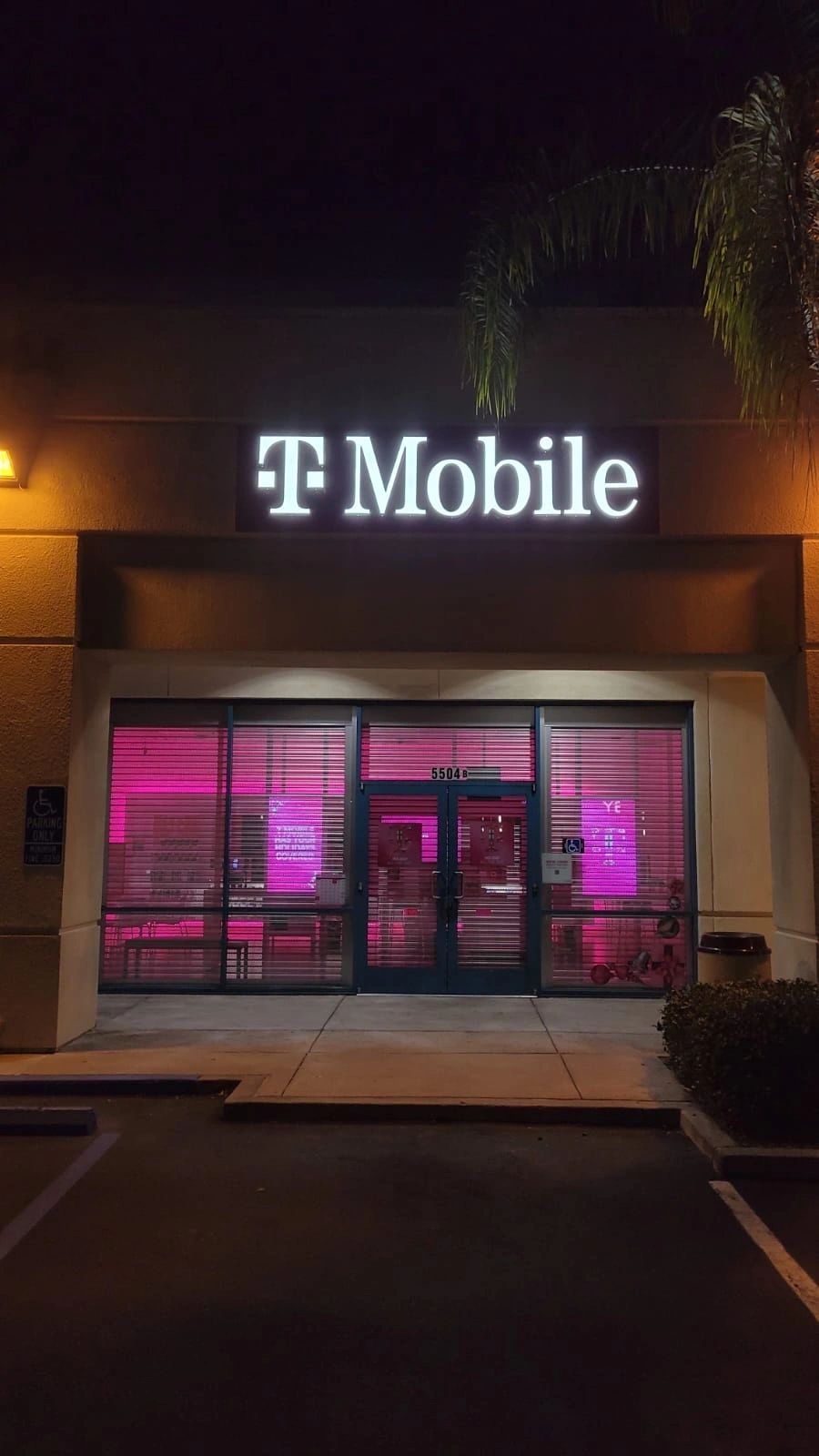 T-Mobile storefront at night with pink-lit windows and illuminated sign