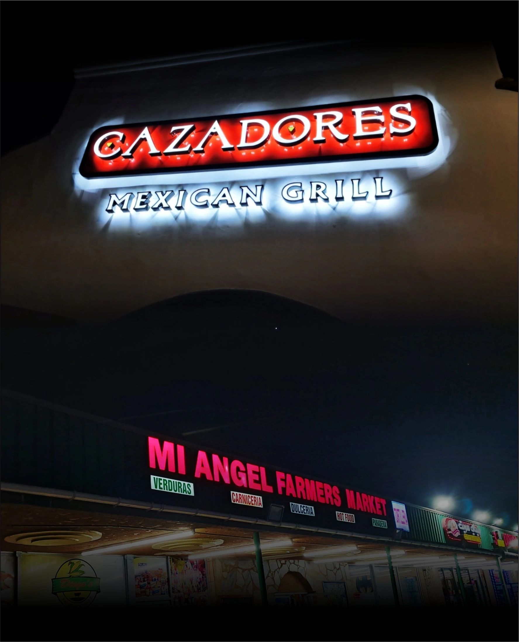 Night view of a restaurant sign reading “Cazadores Mexican Grill” with “Mi Angel” below.