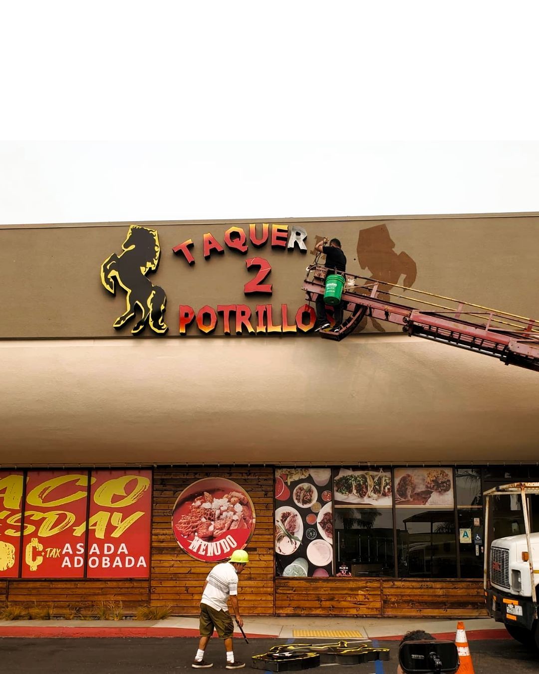 Sign for Taquero 2 Potrillo above a storefront with a man walking below it