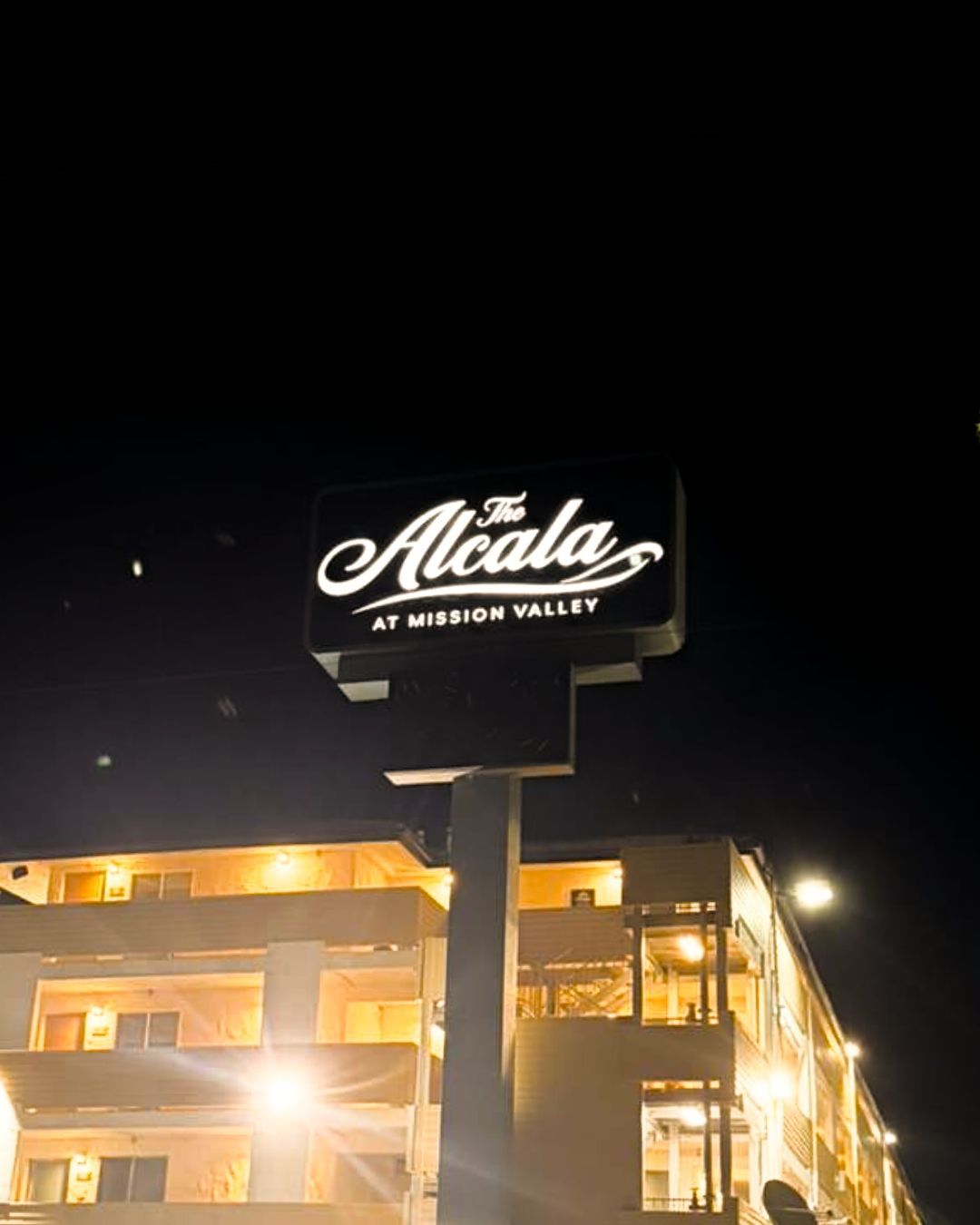 The Alcala at night, a lit-up hotel sign above a brightly illuminated building.
