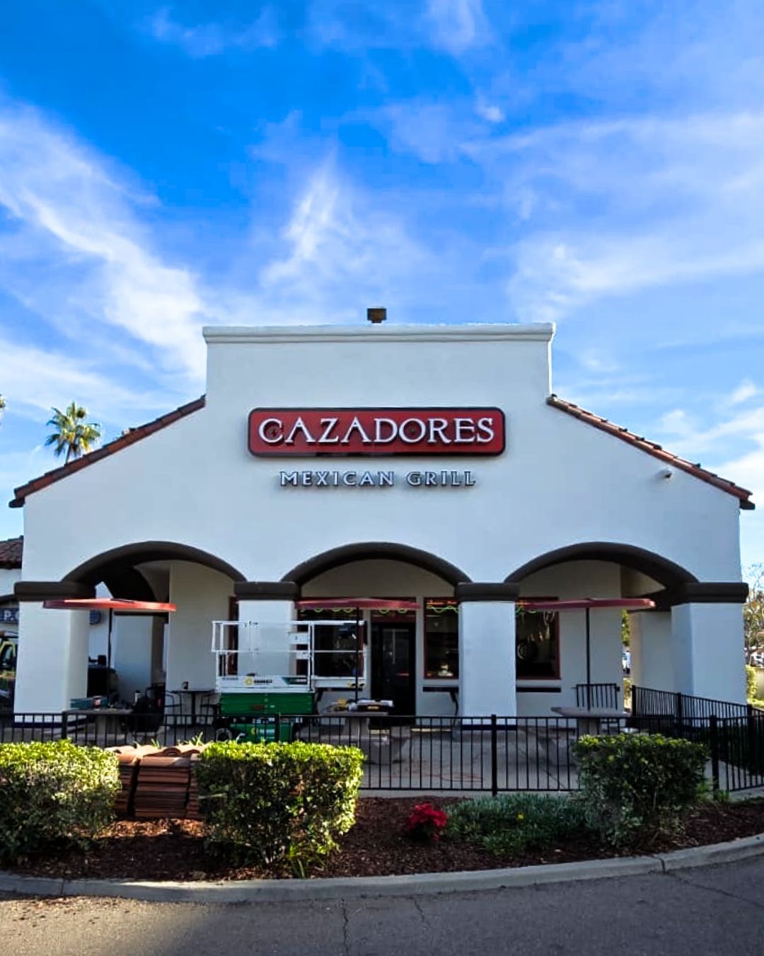 Cazadores restaurant exterior with white stucco facade and red sign under a blue sky