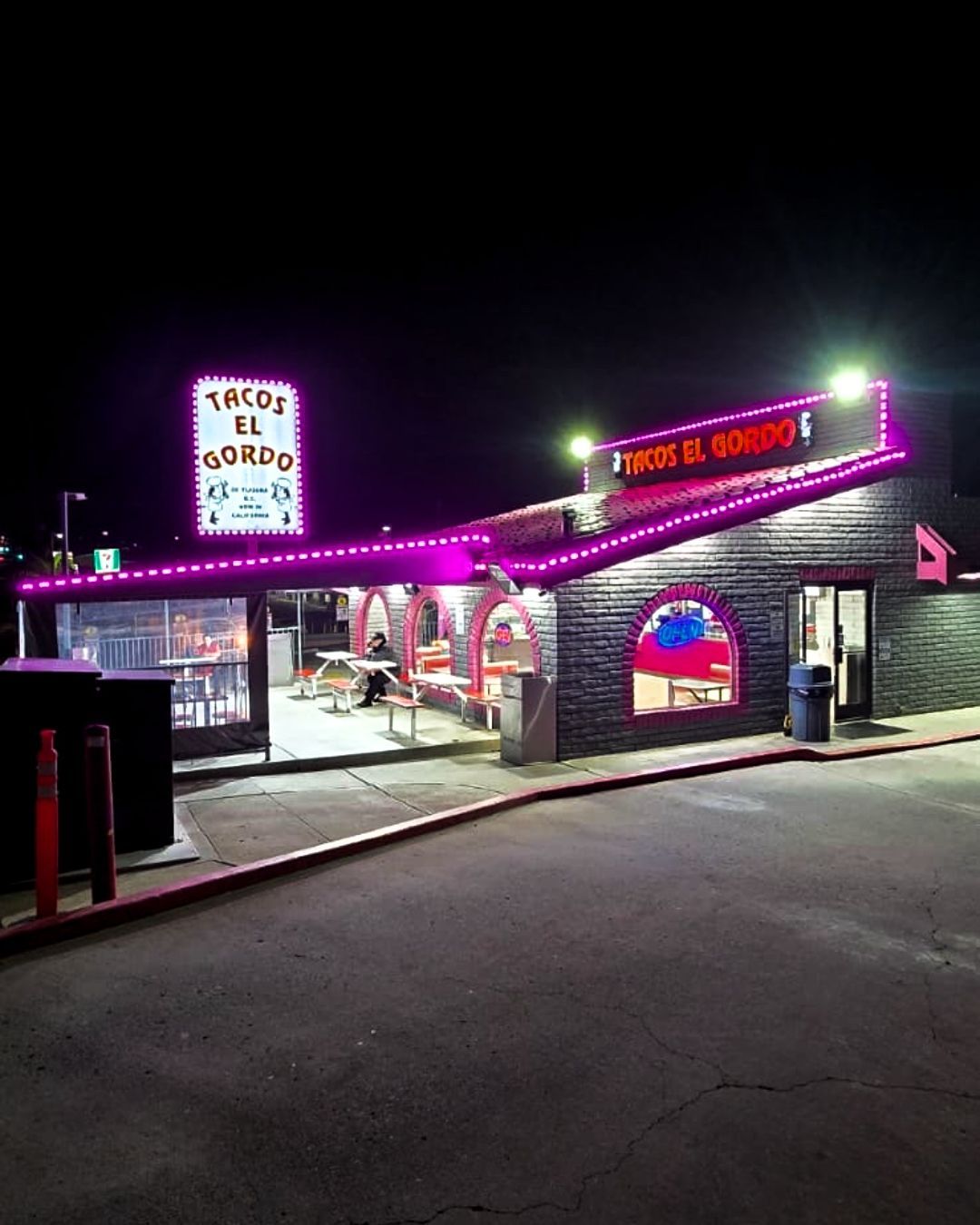 Neon-lit roadside diner at night with pink lights, arched windows, and a curved driveway.