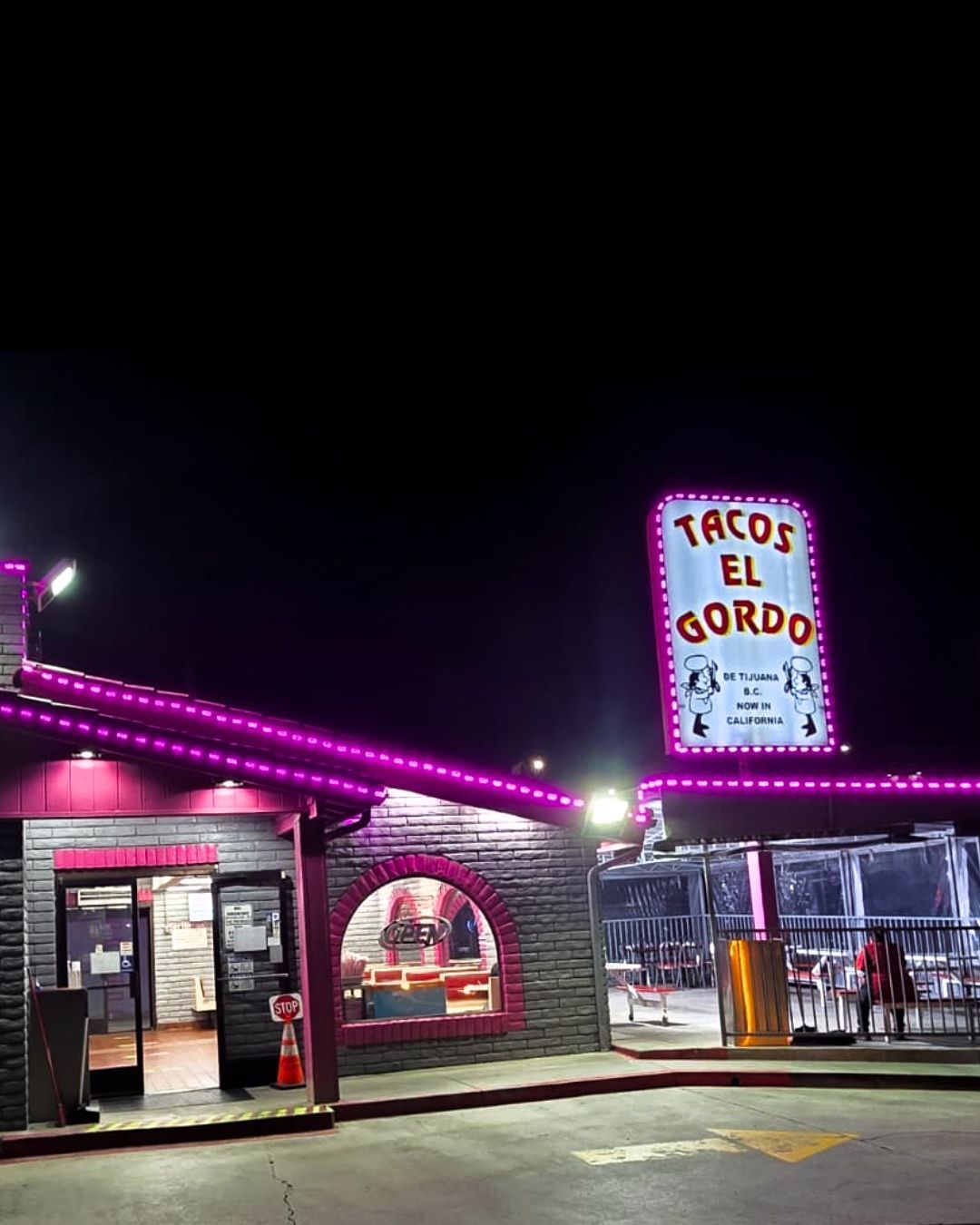 Neon-lit Taco El Gordo restaurant at night with pink trim and a glowing sign