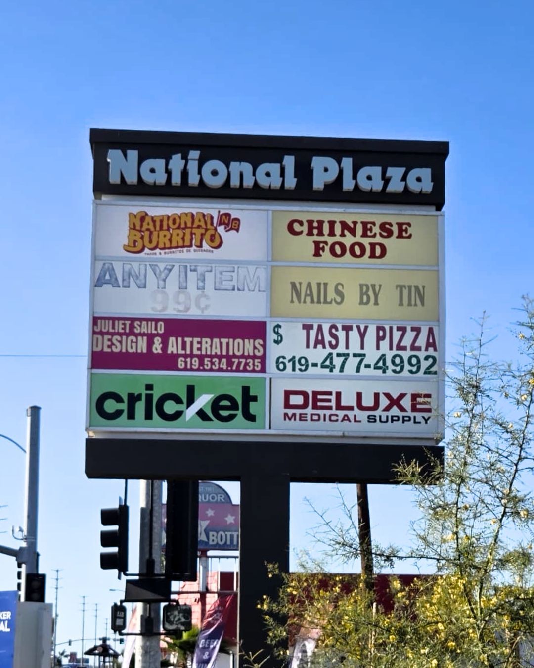 National Plaza shopping center sign with multiple business listings under a blue sky