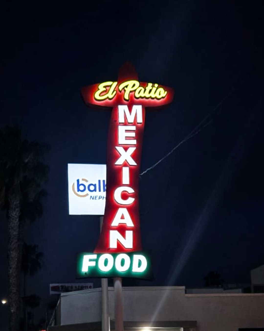 Neon sign for El Patio Mexican Food glowing red, yellow, and green at night
