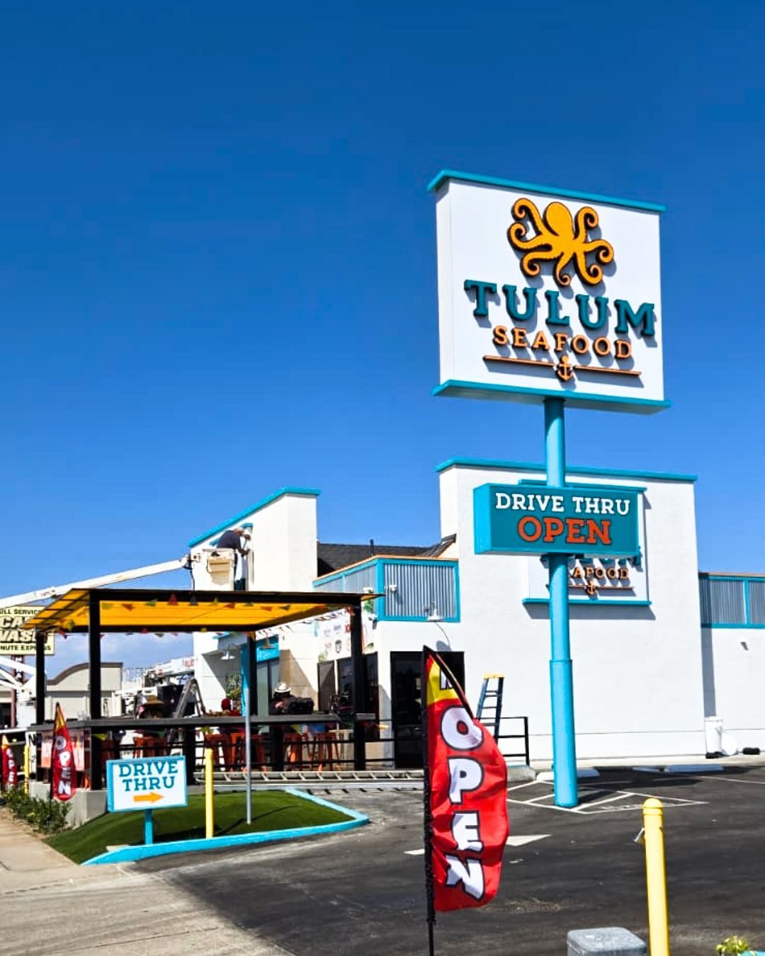 Tulum Beach sign and open drive-thru stand under a bright blue sky