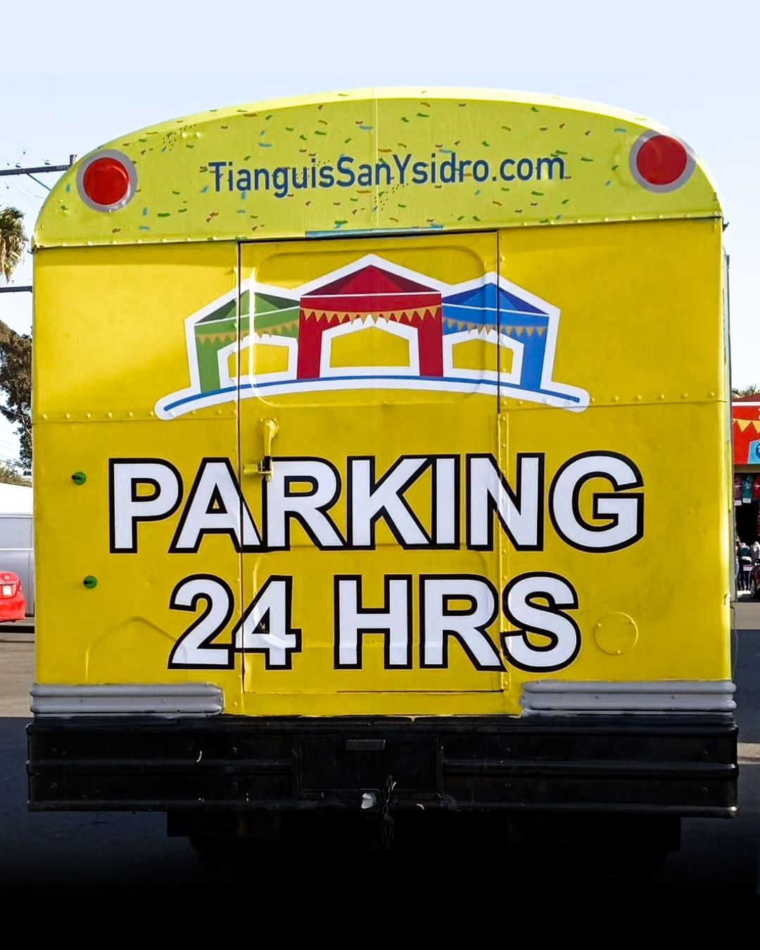Yellow parking sign on vehicle rear reading PARKING 24 HRS with colorful logo above