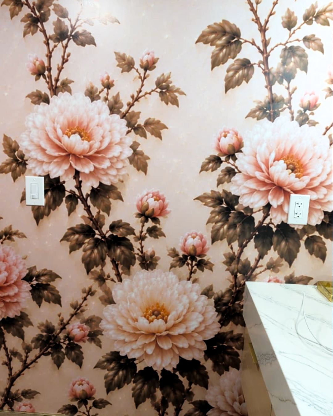 Pink floral wallpaper with large peach peonies and a white countertop in the corner