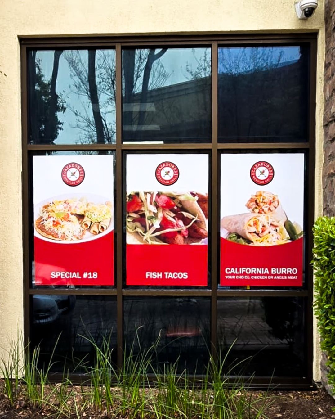 Restaurant window with three food posters labeled Special 418, Fish Tacos, and California Burrito