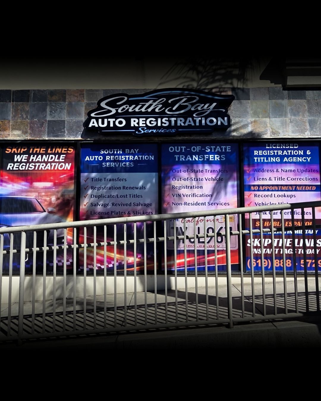 South Side Auto Registration storefront at night behind a metal fence, with illuminated service signs.
