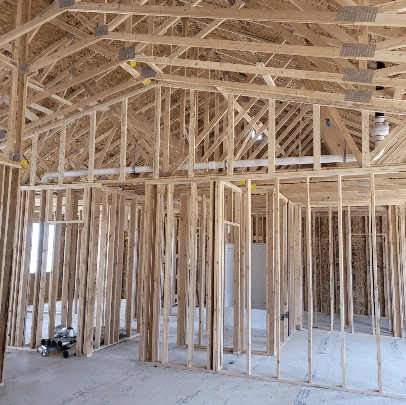 Interior of a house under construction with exposed wooden framing and trusses