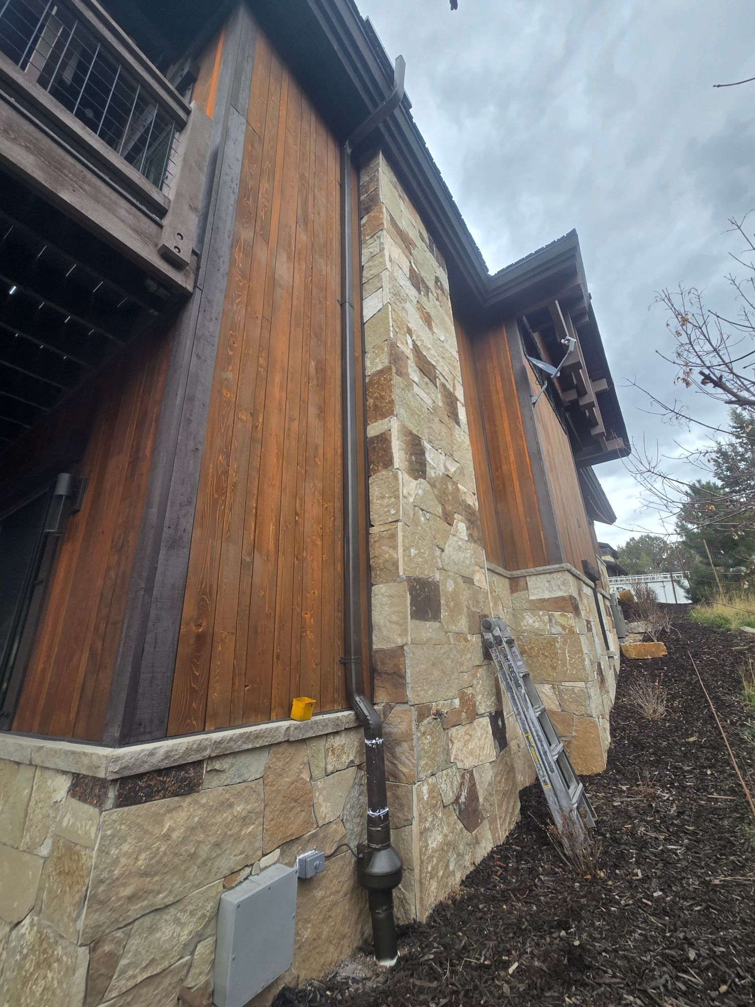 Wood-and-stone building exterior with a steep roof under an overcast sky