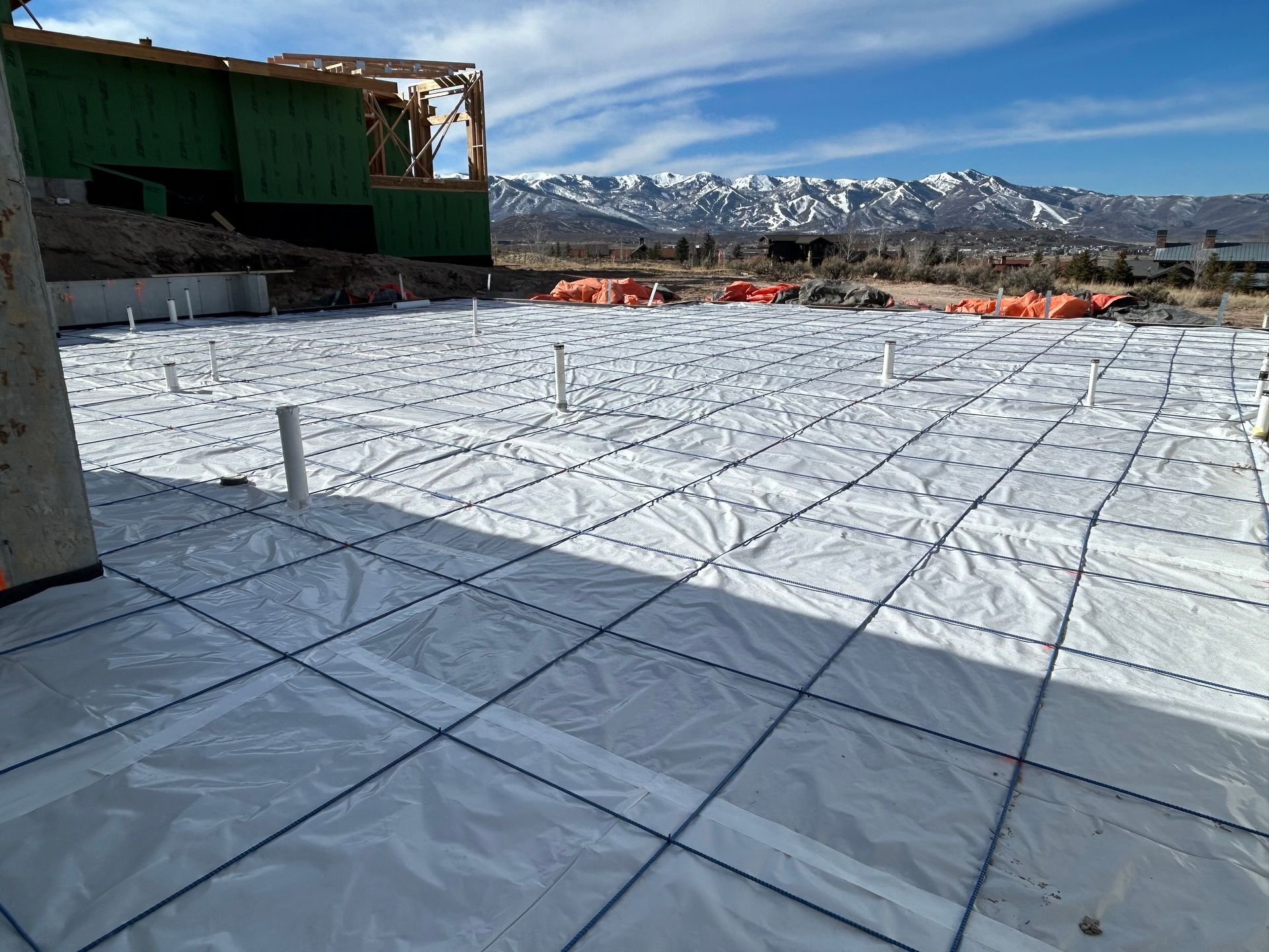 Snow-covered rooftop construction site with mountains in the background under a blue sky