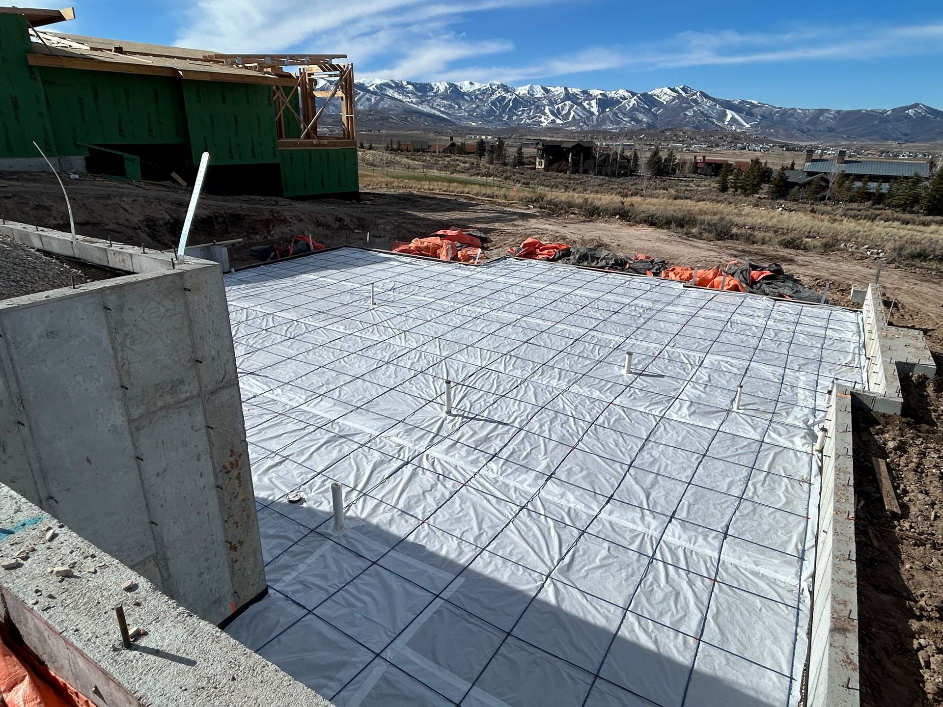 Concrete foundation slab with rebar mesh at a construction site, mountains in the background