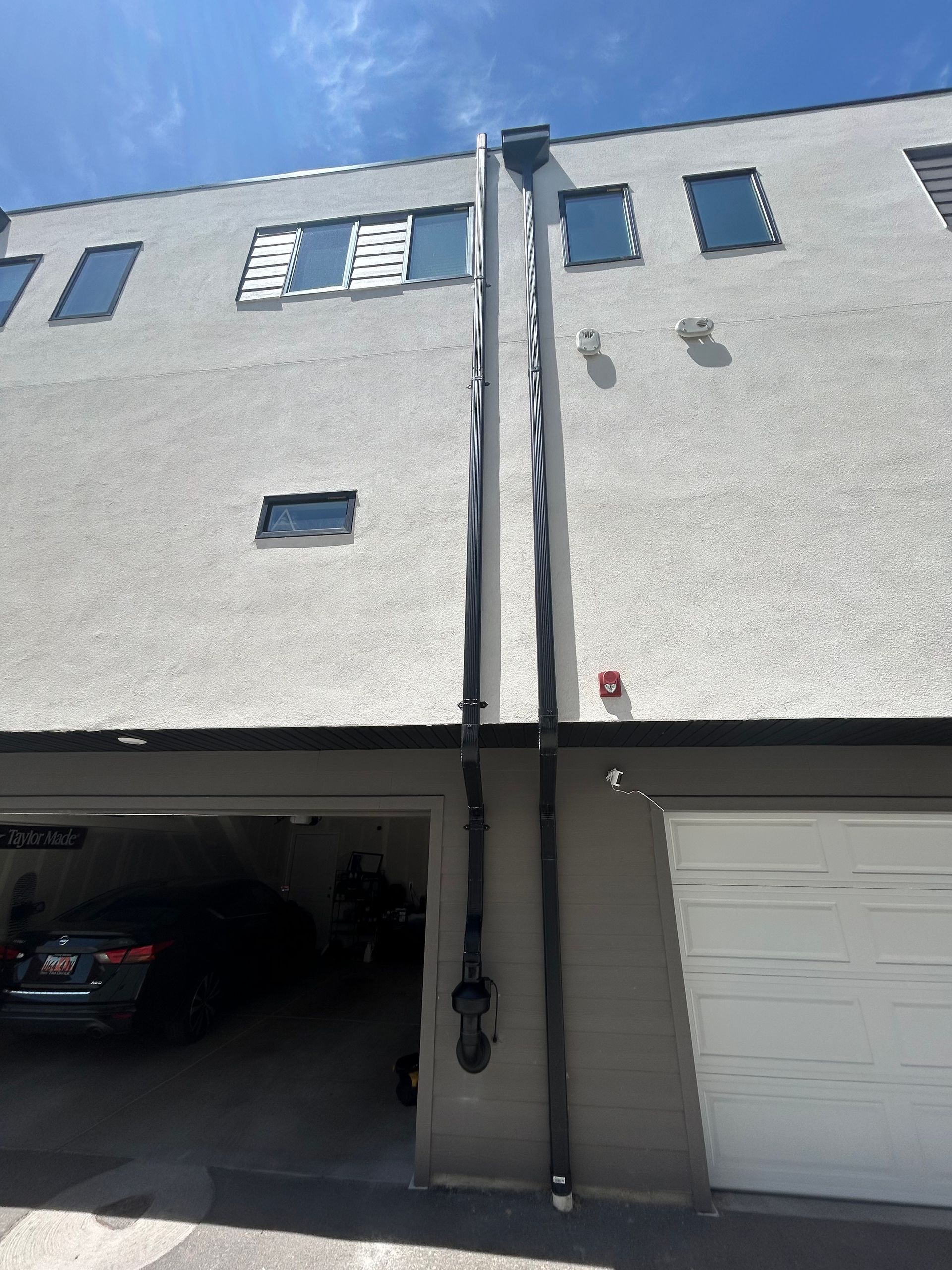 Row of light-gray townhouses with garages and windows, viewed from the street