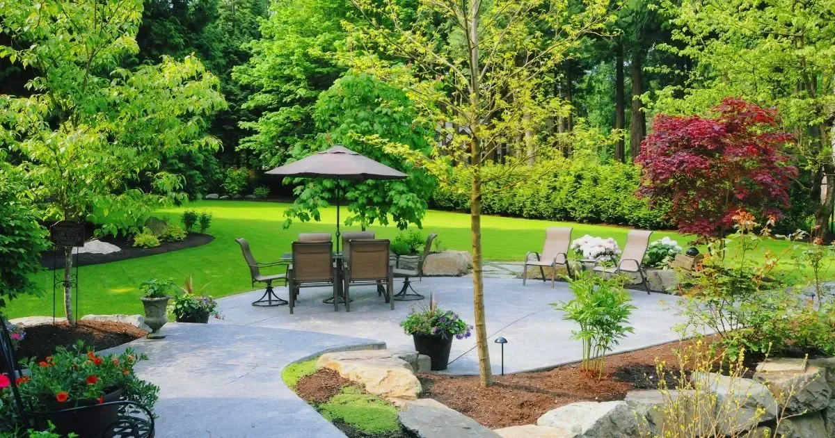 Garden patio with umbrella, stone seating, and lush green landscaping