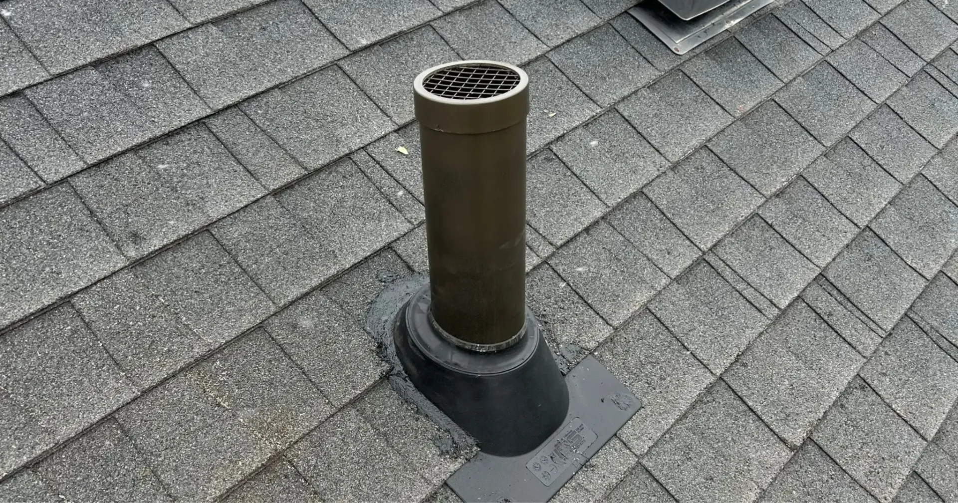 Roof vent pipe protruding from gray shingle roofing.