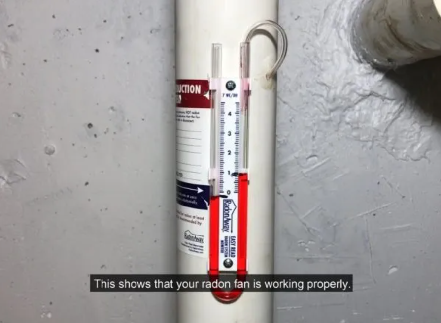 Radon test kit with red indicator next to a wall, showing the fan is working properly.