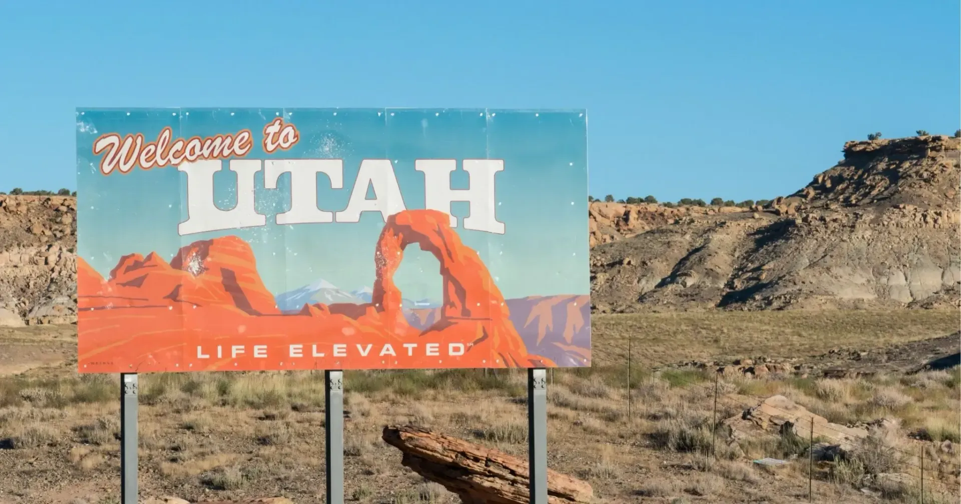 Welcome to Utah roadside sign against a rocky desert landscape under a blue sky