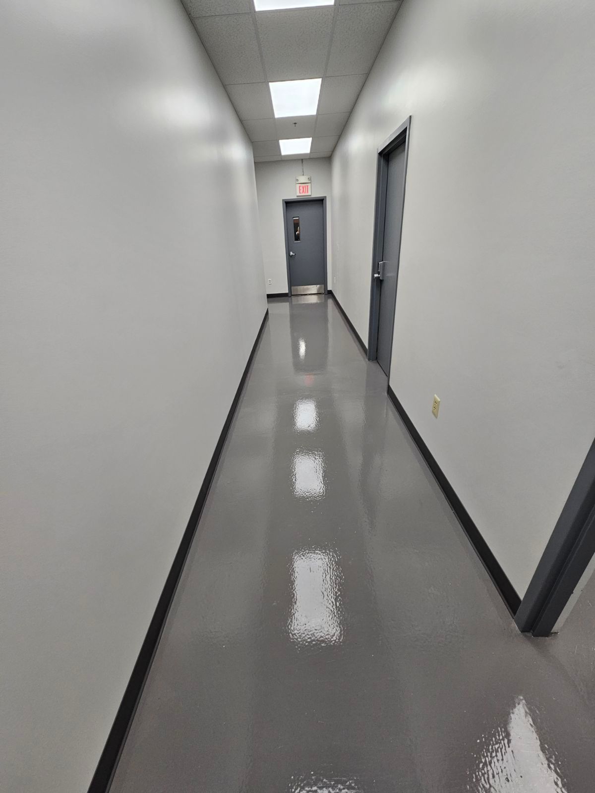 A long hallway with white walls and a shiny floor.