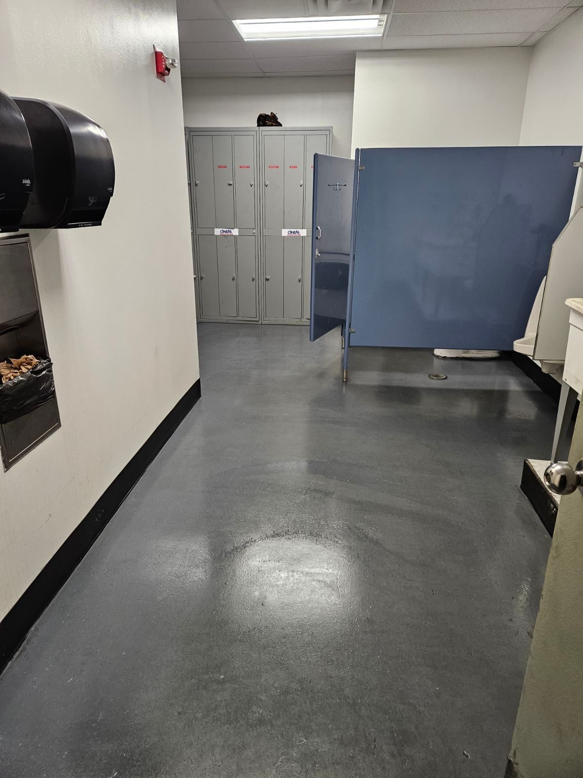A hallway in a building with lockers and a toilet.