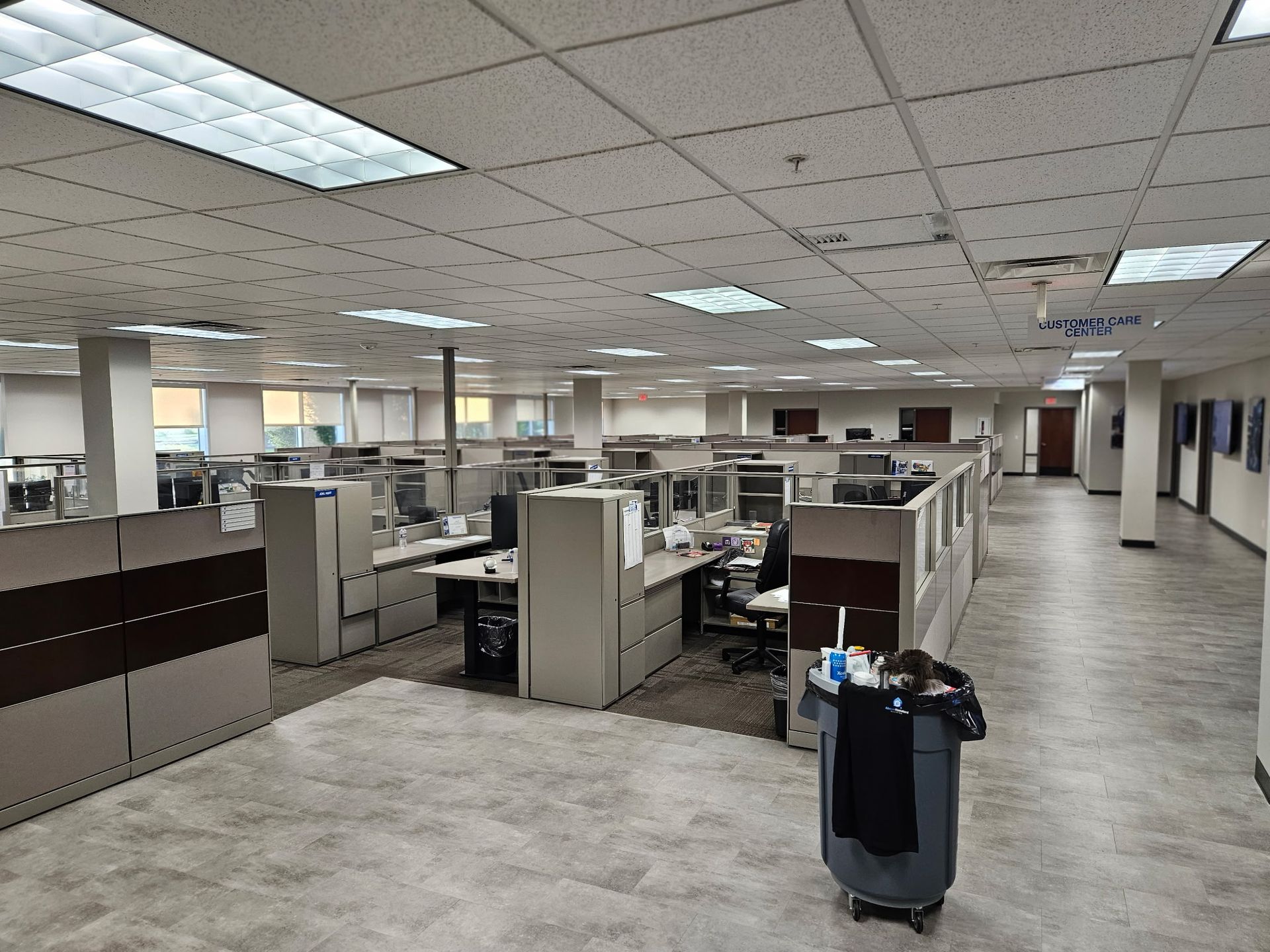 A large empty office with cubicles and a trash can in the middle.