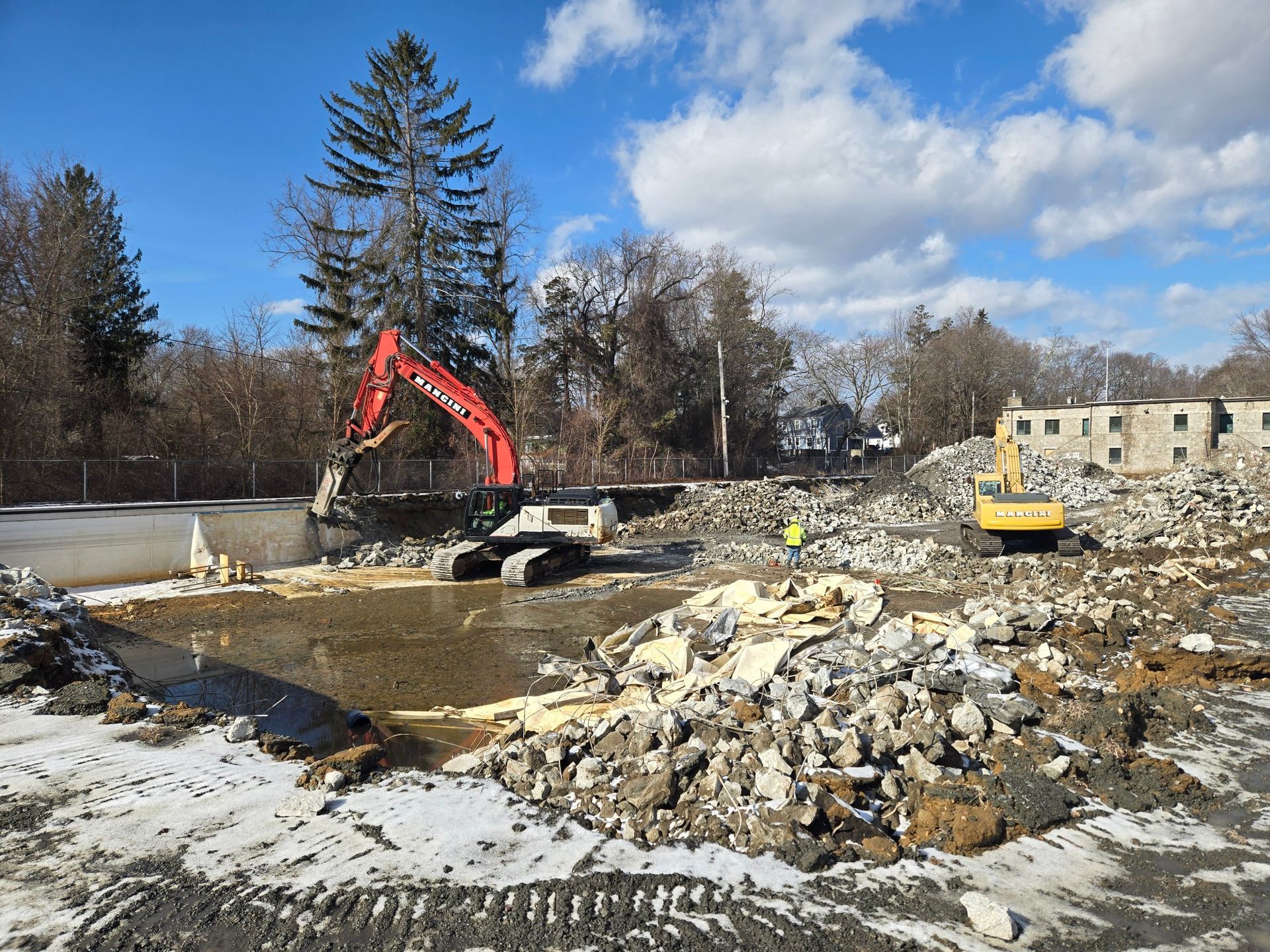 Construction site with excavator and rubble under a cloudy sky
