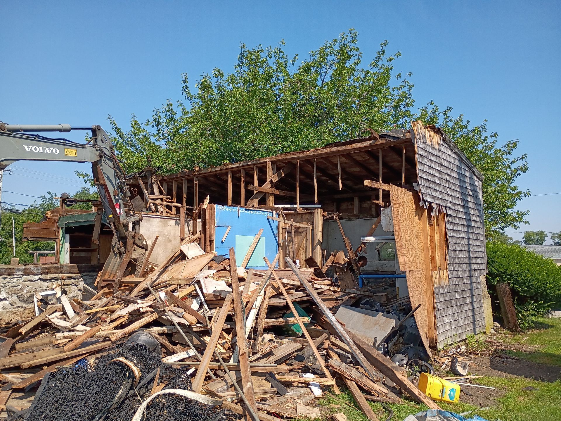 Collapsed building with rubble and debris piled outside under a clear blue sky