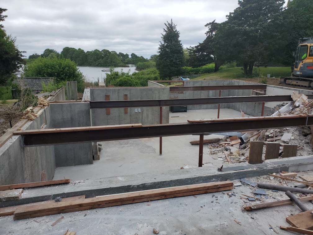 Concrete foundation site with steel beams and debris in a partially built structure outdoors