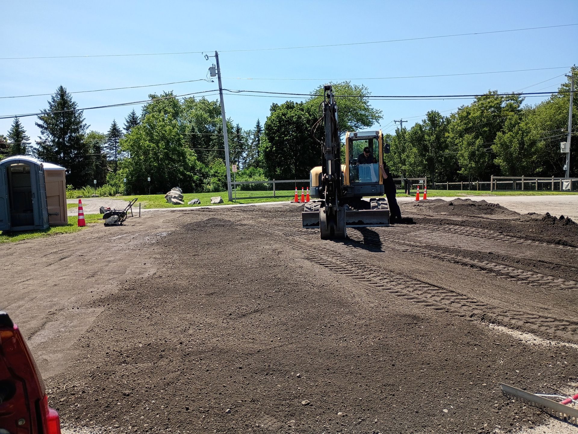 Construction site with an excavator leveling dirt under a clear blue sky