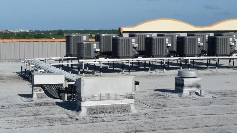 Rooftop with multiple air conditioning units on raised platforms, against a clear sky.