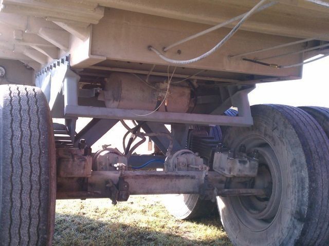 Undercarriage of a truck trailer, showing axles, wheels, and a supporting framework.