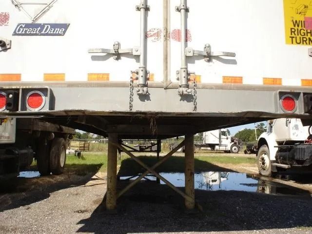 A semi-trailer with a damaged undercarriage. Two rear tires, side by side.