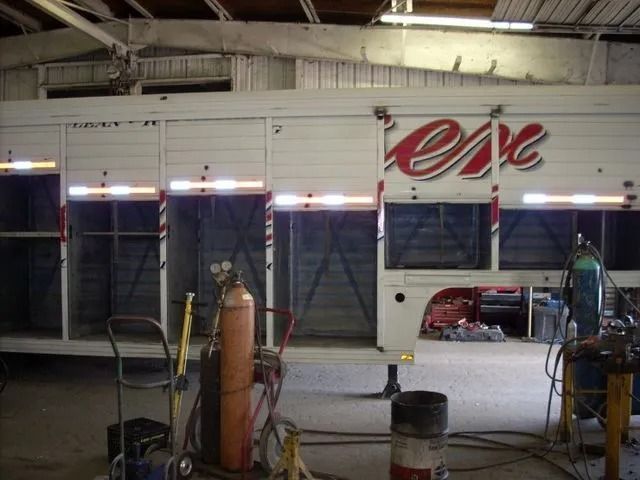 Horse trailer being worked on in a workshop with welding equipment visible.