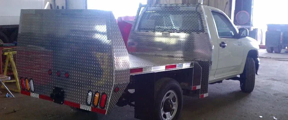 White flatbed truck with diamond plate bed and toolboxes.