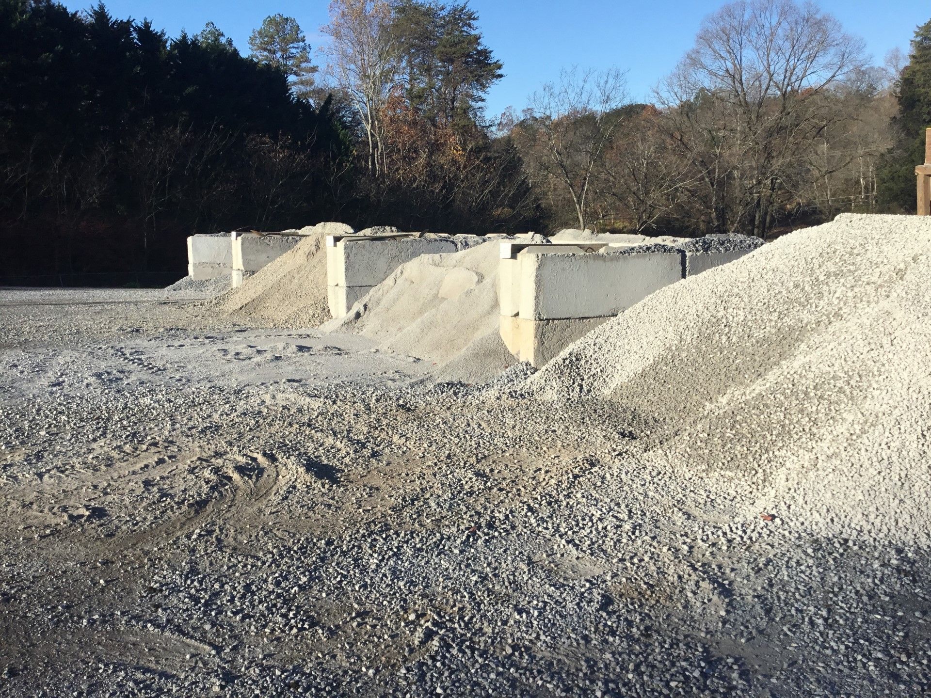 Gravel and sand piles next to concrete blocks outdoors under a clear sky.