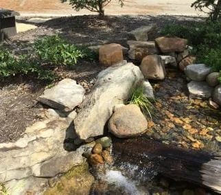 Small waterfall feature with rocks and greenery in a garden setting.