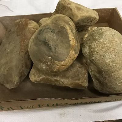 Brown river rocks in a cardboard box, likely for landscaping.