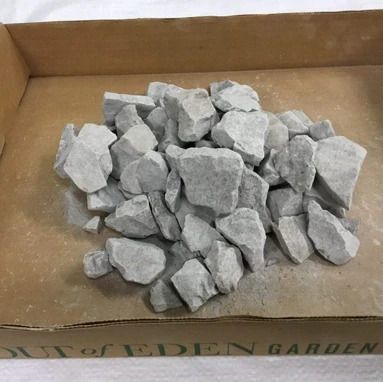 Pile of light gray rocks in a cardboard box, possibly landscaping stones.