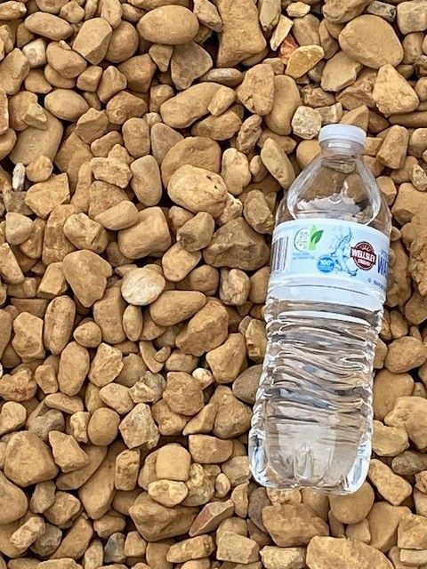 Clear water bottle lying on tan rocks or pebbles