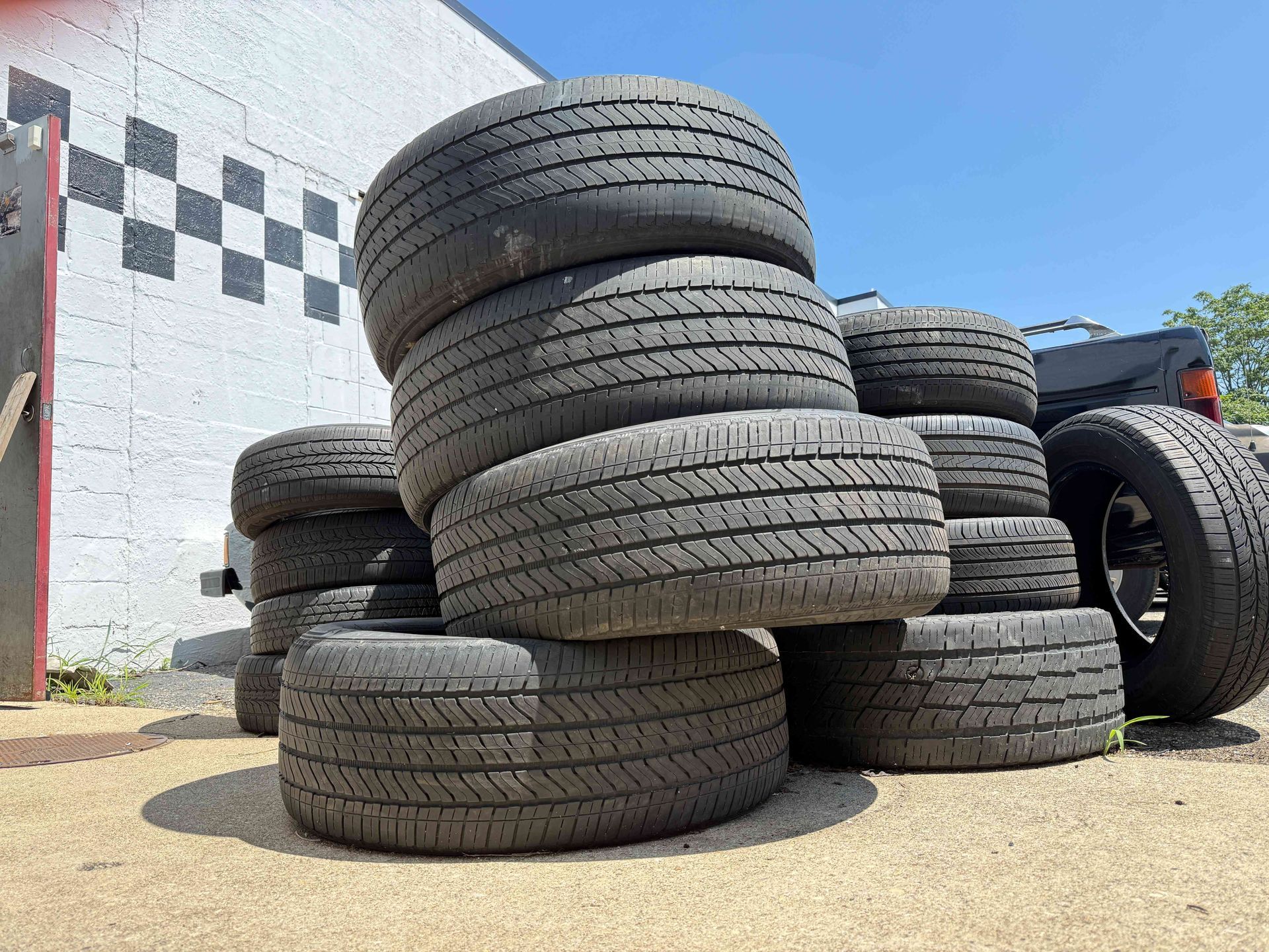 Stacked used tires piled outside a building under a clear blue sky.