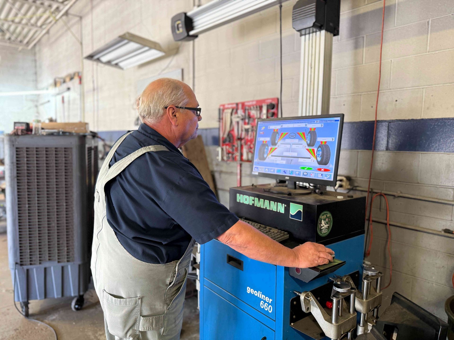 Man operating a blue industrial machine in a workshop, viewing its screen.