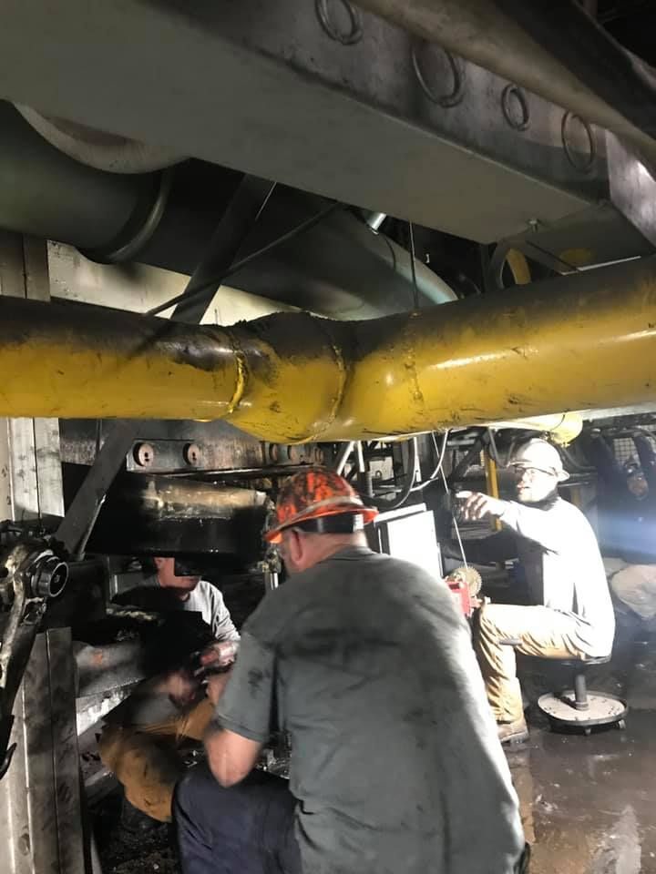 A group of men are working on a machine in a factory.