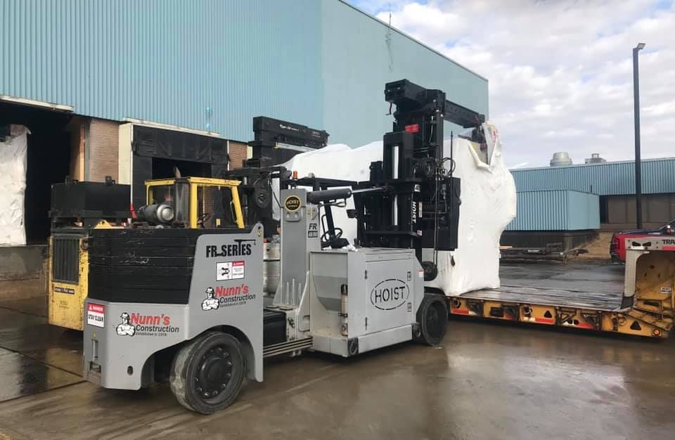 A forklift is carrying a large object in a warehouse.