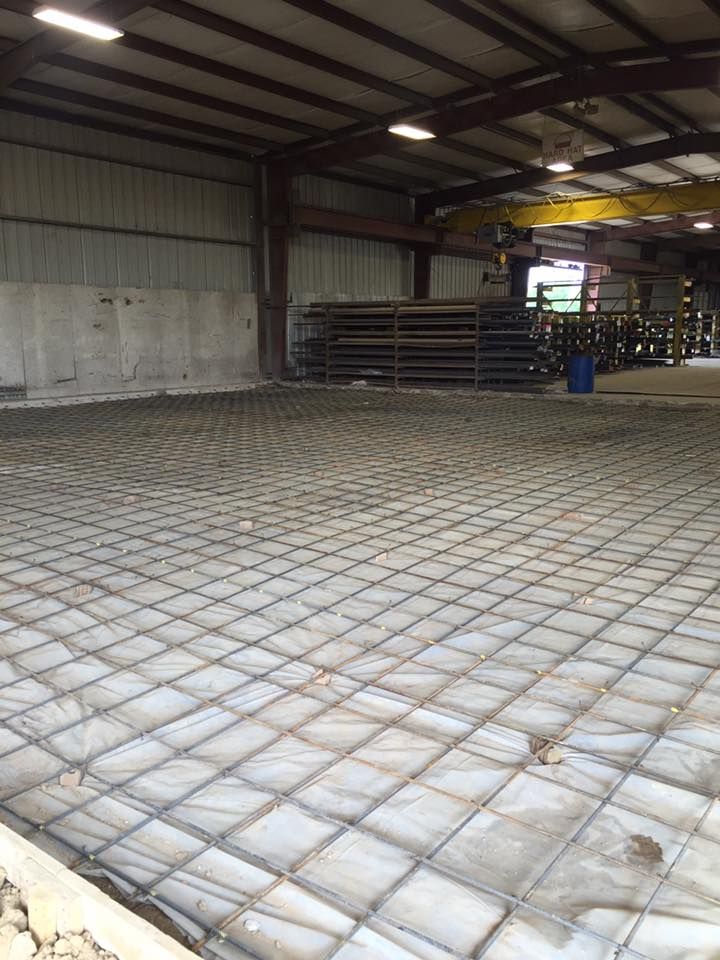 A large warehouse with a concrete floor and a crane in the background.