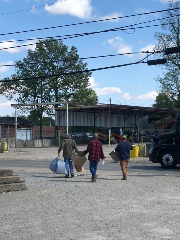 Two men carrying boxes are walking towards a truck