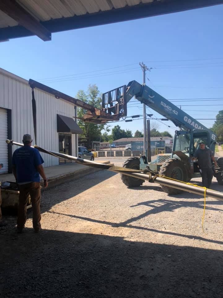 A man is standing next to a forklift in front of a building.