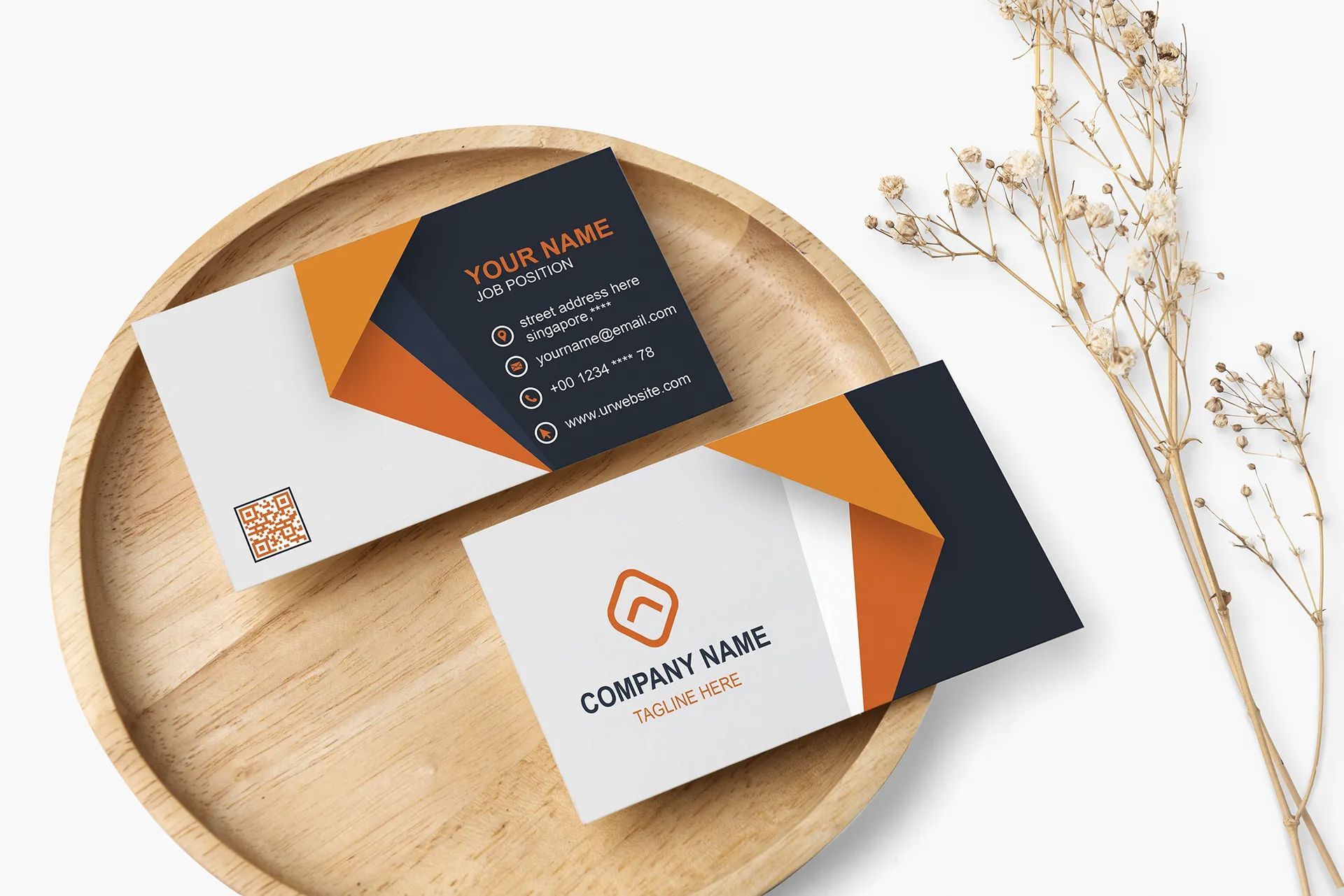 Business cards on a wooden tray with dried flowers, featuring orange, navy, and white geometric designs.