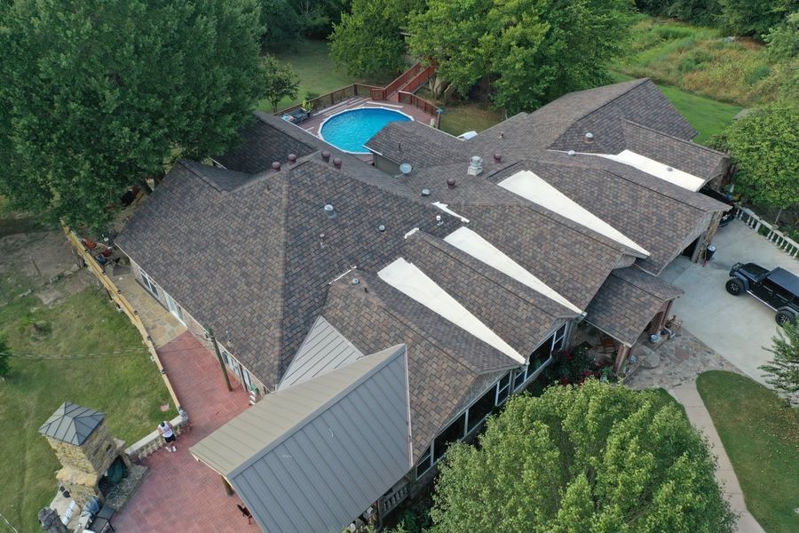 Aerial view of a house with a brown roof and a pool in the backyard.