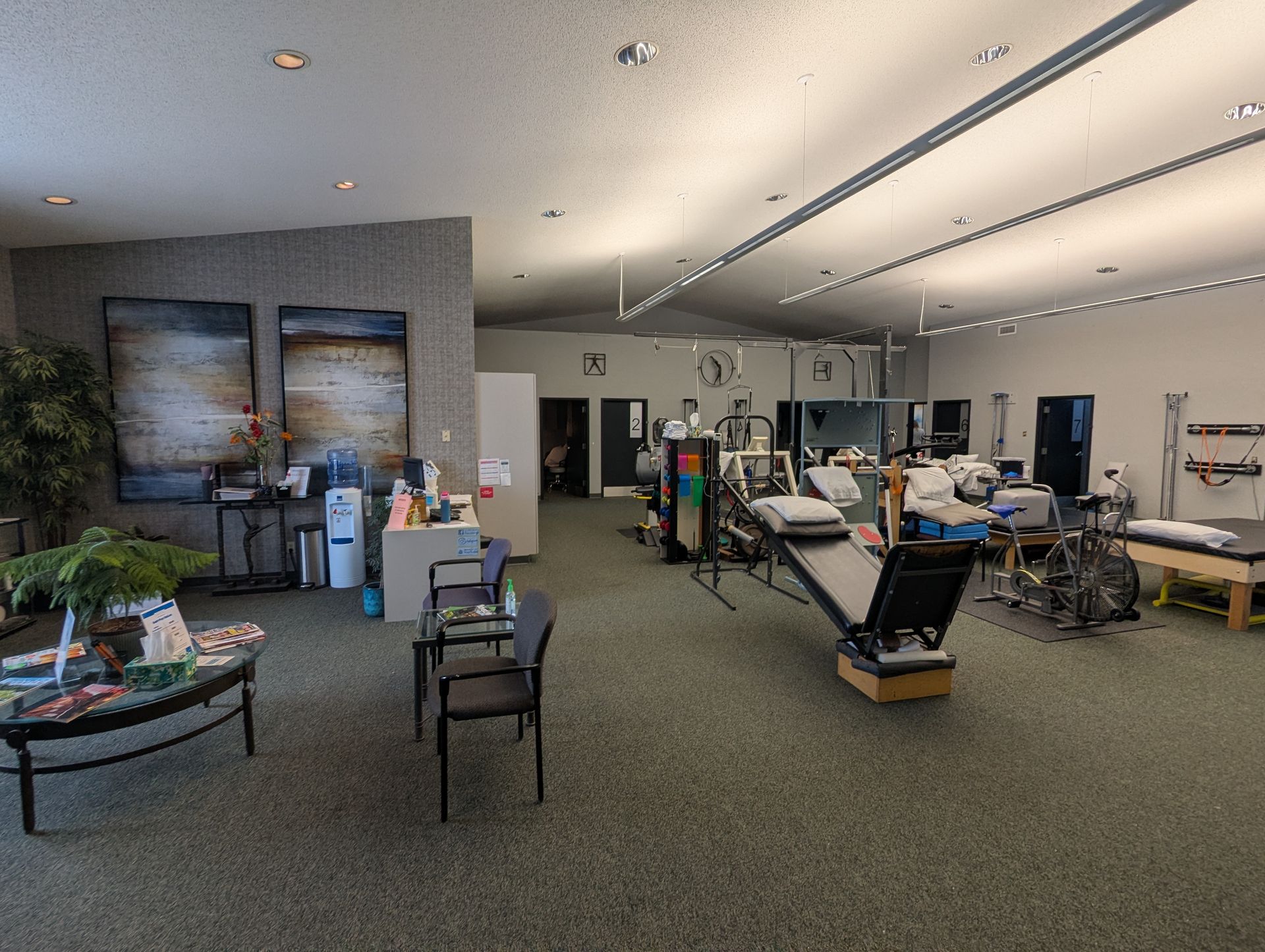Interior of a physical therapy clinic with various exercise machines, treatment tables, and waiting area.